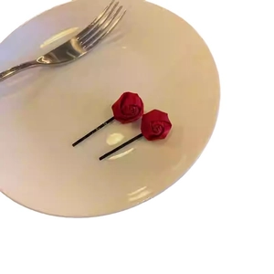 Paio di fermagli per capelli con rosa rossa e fiocchi su piatto bianco e forchetta