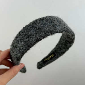 Détail d'un bandeau en peluche gris foncé avec texture bouclée et étiquette de marque interne