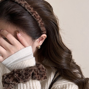 Detailed view of leopard print plush headband and hair tie set with golden stud earring