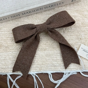 Barrette à cheveux élégante en tricot marron foncé avec nœud rétro sur un fond en tissu doux