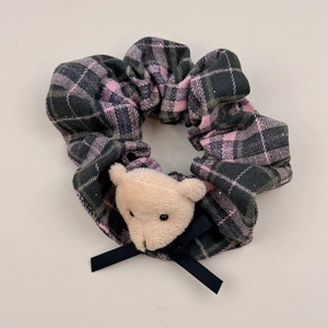 Dettaglio dell'elastico in tessuto a quadretti con orsetto di peluche e fiocco nero