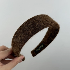 Vue détaillée du serre-tête en peluche marron foncé avec texture en laine douce et étiquette