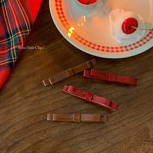 Set of four vintage bow hair clips in deep red and brown colors on a wooden table