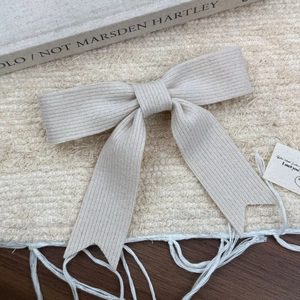 Détail de la pince à cheveux en tricot crème avec une élégante texture côtelée