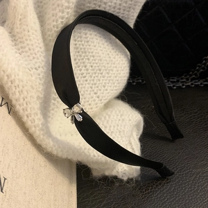 Dettaglio del cerchietto in raso nero con fiocco di zirconi scintillanti su maglia