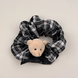 Dettaglio dell'elastico a scacchi con orsetto di peluche e fiocco in nastro nero