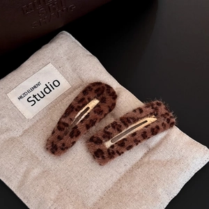 Detailed view of leopard print plush hair clips set with gold metal base on fabric