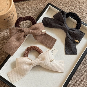 Three bow elastic hair ties in brown, dark grey, and beige with knit ribbed texture