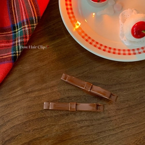 Set of two vintage brown glossy resin bow hair clips on a classic dark wood background