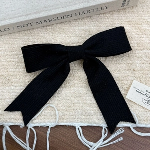 Détail de la texture d'une barrette à nœud noir sur un fond minimaliste élégant