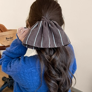 Brown striped oversized bow hair scrunchie shown on a woman with long dark wavy hair