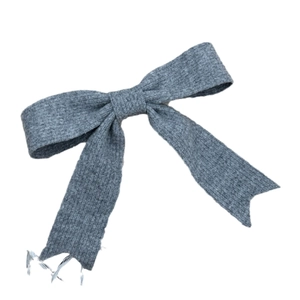 Barrette à cheveux avec nœud en tricot gris et pompon sur un fond blanc épuré