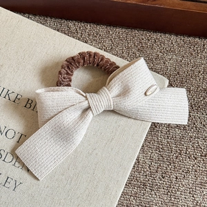 Close-up of cream knit bow hair tie with velvet scrunchie and Love Forever gold metal charm