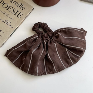 Detail of dark brown striped oversized scrunchie with pleated suede fabric texture