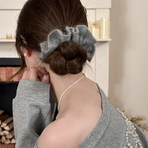 Vue détaillée du chouchou gris en tricot porté sur un chignon de style classique