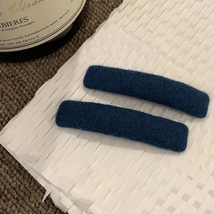 Dettaglio dei fermagli per capelli in feltro blu scuro su carta con finitura morbida
