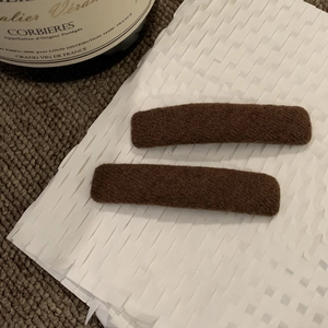 Dettaglio di un paio di fermagli per capelli marroni rettangolari in tessuto lavorato