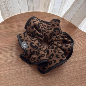 Detailed view of leopard print knit scrunchie with soft texture and brand label