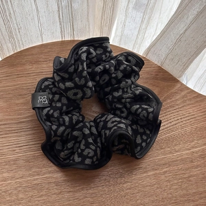 Detail of grey leopard print scrunchie with soft brushed texture and black brand label