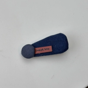 Detail einer dunkelblauen Strick-Haarklammer mit braunem Lederetikett und Sweet Love Text