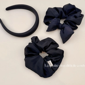 Close-up of black satin hair scrunchies and matte headband with Hand Made label details