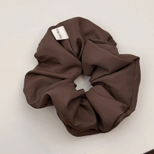 Detail shot of a dark brown scrunchie showing fine fabric texture and Hand Made label