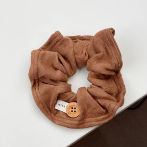 Detail eines Stoff-Haargummis in Caramel mit Holzknopf und gewebtem 'made with love' Etikett