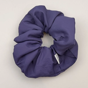 Detail of a handmade deep purple pleated puffy scrunchie featuring a Hand Made label