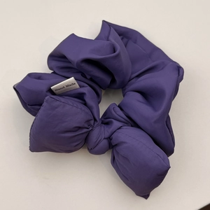 Close-up of purple bubble fabric bow scrunchie featuring a white Hand Made textile label
