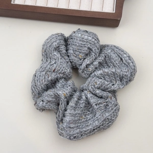 Gros plan sur un chouchou en grosse maille grise avec points colorés et texture douce