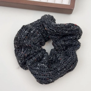 Détail d'un chouchou en grosse maille gris foncé avec des fibres de tweed colorées