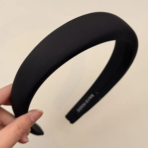 Detail of handmade black padded headband with silk-like finish and woven label