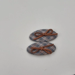 Detail of two plaid fabric hair clips with brown bows in retro preppy style