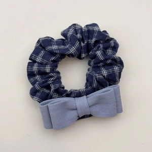 Detail eines blau karierten Haargummis mit einer hellblauen Schleife aus Twill-Stoff