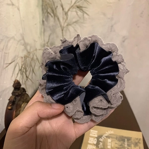 Detailed close-up of blue velvet scrunchie with delicate grey lace embroidery edges
