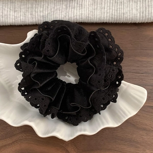 Detail shot of a black velvet scrunchie with delicate lace edges on a ceramic plate