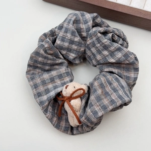 Detail view of plaid scrunchie with cute bear head decor and brown ribbon bow
