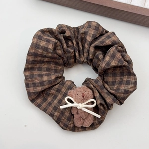 Detailed shot of a vintage brown plaid scrunchie with a cute plush bear accessory