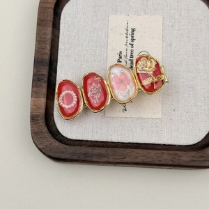 Detail showing vintage red floral hair clip with gold edges and pearl inlay on wood