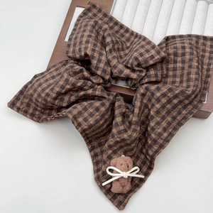 Detailed shot of brown plaid hair scrunchie with a cute plush bear and bow accessory