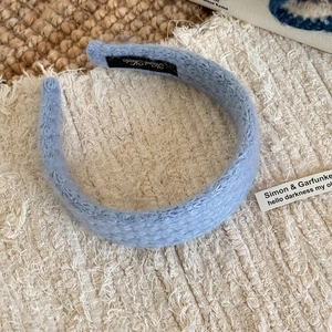 Detail of light blue quilted headband with 'Hand Made' label on soft knit texture