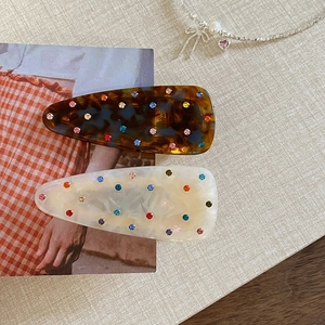 French style hair clips with colorful rhinestones and marble texture on a beige background