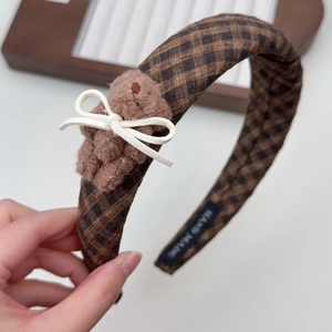 Detail of checkered headband featuring a plush brown bear and white bow with handmade label