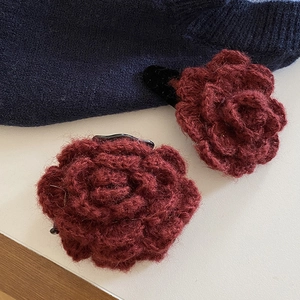 Detail of handmade crochet burgundy rose hair clips with soft yarn texture and metal grip