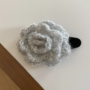 Detailed close-up of a handmade grey knitted rose hair claw clip with subtle sparkles