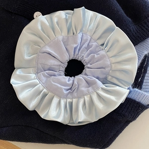 Scrunchie in raso blu e cotone viola con volant su sfondo in maglia blu scuro