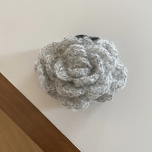 Close-up detail of grey knitted rose flower hair claw clip with delicate yarn texture
