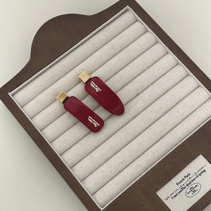 Detail view of red vintage acetate hair clips with gold metal base on wooden tray