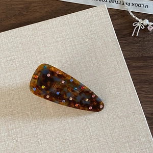 Detail of tortoiseshell hair clip with colorful rhinestones on vintage wooden background