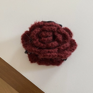 Detail of burgundy knitted rose hair claw clip with handmade wool petal texture